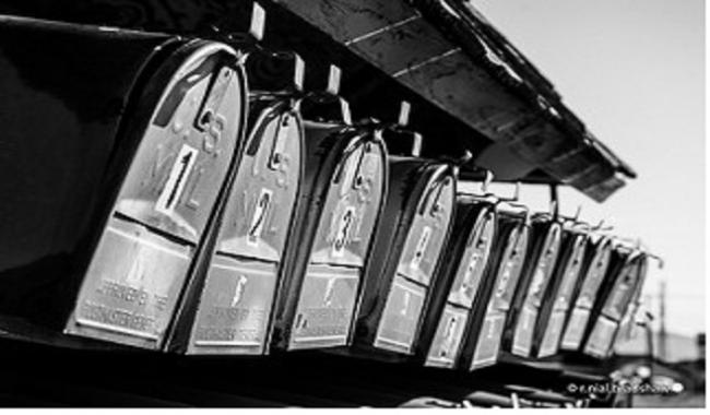 Up close black and white image of mailboxes in a row