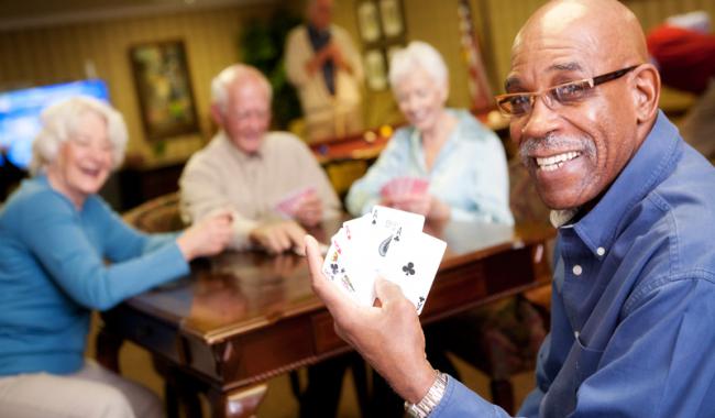 Four seniors playing cards and showing four aces in hand