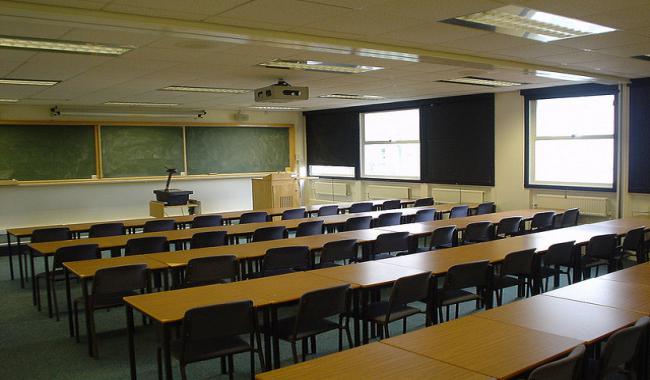 An empty classroom with rows of desk and chairs.