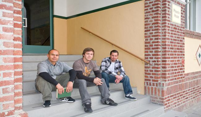 3 males sitting on the steps of a building