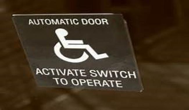 An image of push button with universal access symbol that reads "activate switch to operate" to open door