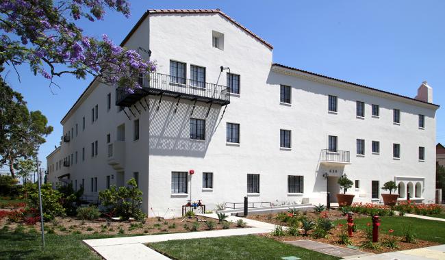 The front and side of an affordable multi-family housing/apartment building with green landscaping